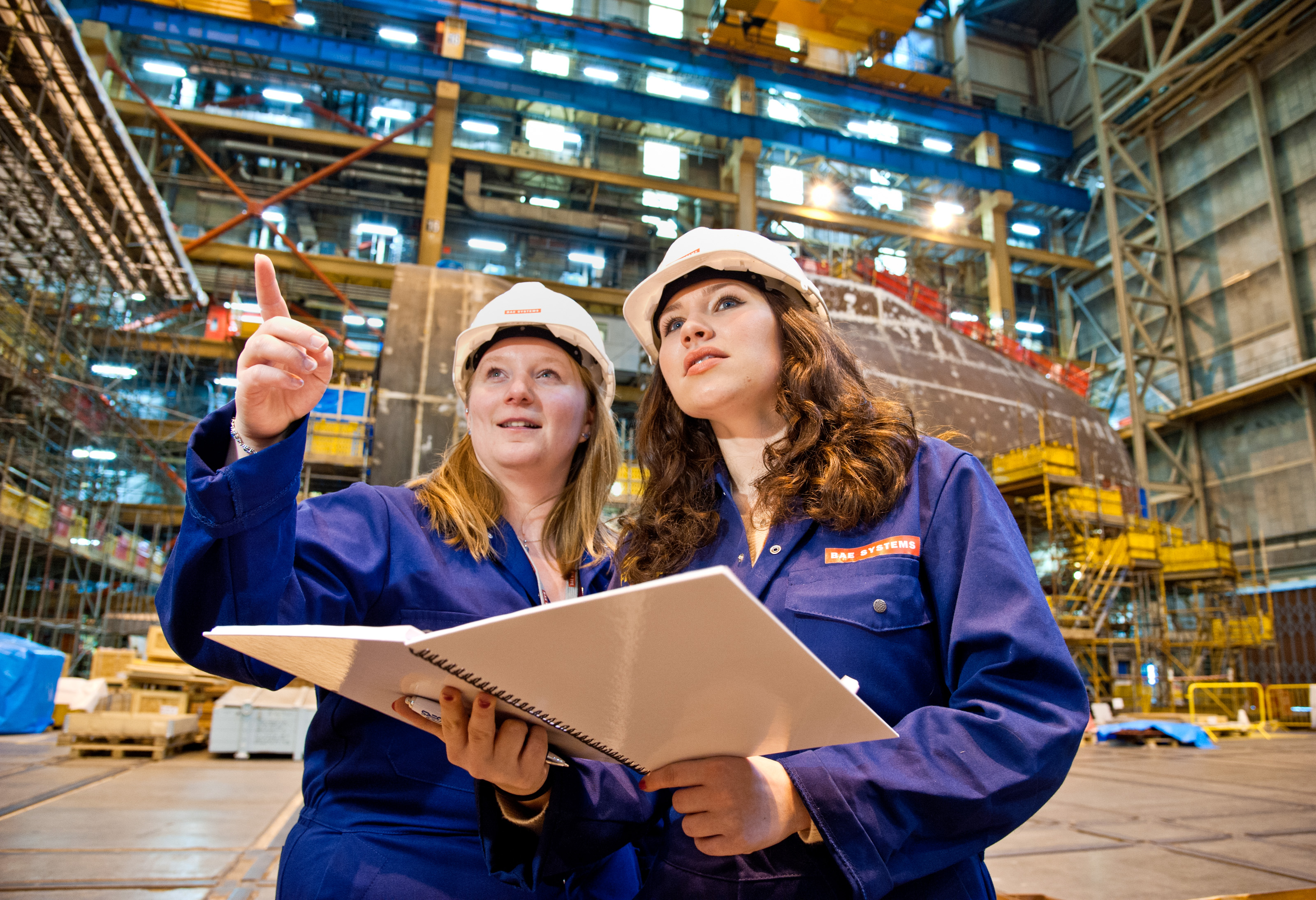 Two women in hardhats looking at facility
